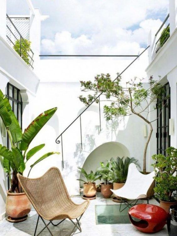 a small terrace with a couple of chairs, potted plants, and a bold red candle lantern is chic and stylish
