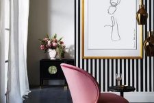 a sophisticated living room with a black and white accent wall, a pink chair and a pretty artwork and refined furniture