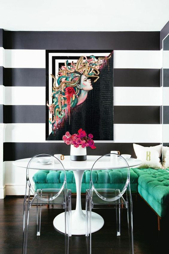 a stunning dining space with a green corner bench, a round table, acrylic chairs and a bold artwork