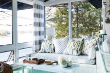 a stylish beach sunroom with an aqua floor, white wooden furniture and printed textiles