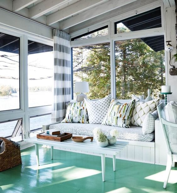 a stylish beach sunroom with an aqua floor, white wooden furniture and printed textiles