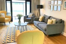 a stylish grey and yellow living room with a geo printed rug, yellow chairs, a grey sofa and a grey chair, black lampshade lamps