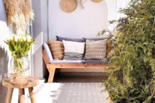 a summer balcony in neutrals, with wooden furniture, crate pots with greenery, decorative baskets, pampas grass and printed pillows