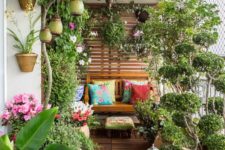 a summer balcony turned into a garden, with potted blooms and greenery, candle lanterns and some wooden furniture