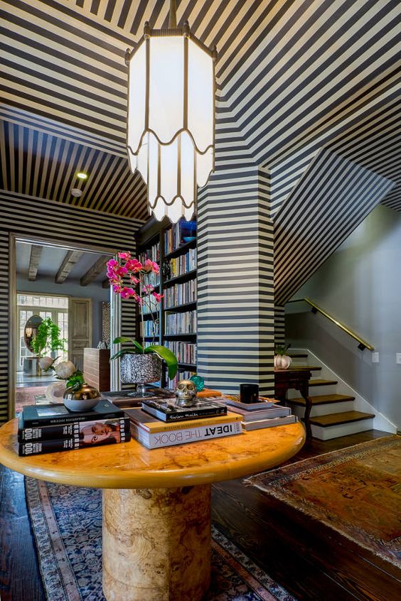 a super bold and eye-catchy space with black and white striped walls and a ceiling that create a mood in the space