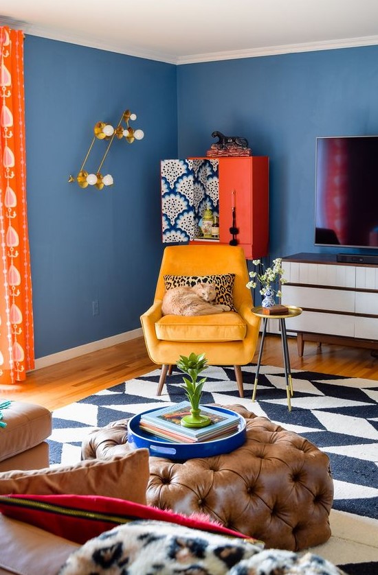 a super bright and fun living room with blue walls, colorful furniture, bold geometric printrug and accessories plus textiles