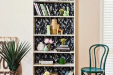 a tall bookcase with black floral backing and decor and books is a stylish idea for any space
