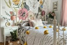 a teenage bedroom with a floral wall, a white metal bed, printed bedding, blush curtains, a cool chandelier and a plant in a basket