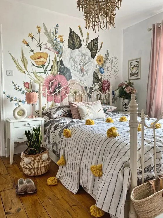 a teenage bedroom with a floral wall, a white metal bed, printed bedding, blush curtains, a cool chandelier and a plant in a basket