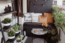 a tiny monochromatic balcony with black and white walls, blakc furniture, potted greenery and blooms and various pillows and rugs