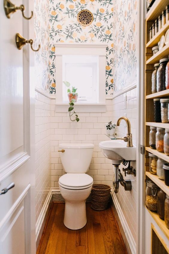 a tiny white powder room with white subway tiles, bright floral wallpaper, a wall mounted sink and white appliances