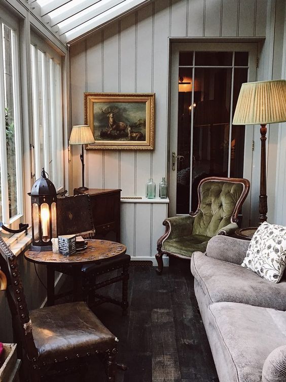 a vintage-inspired sunroom with refined furniture, some lamps and a lantern, an artwork and a sideboard