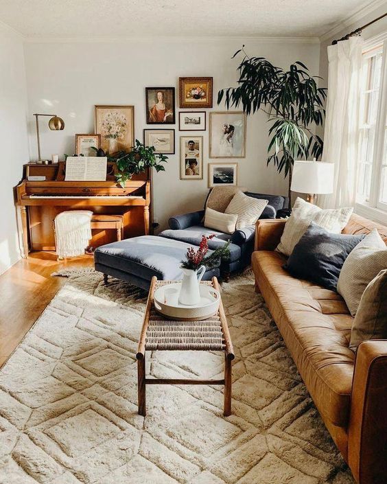 a warm-colored living room with an maber sofa, a woden coffee table, a geometric printed rug, a large lounger, a gallery wall and a potted tree