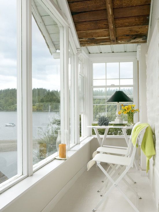 a welcoming tiny sunroom with some foldable chairs and a table, blooms, lamps and candles