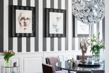 an exquisite dining room with a striped black and white wall, a chic shiny chandelier, lavender chairs and a mirror table