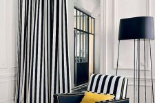 bold and refined interior with paneling and stucco, a striped chair and a matching curtain plus a black floor lamp
