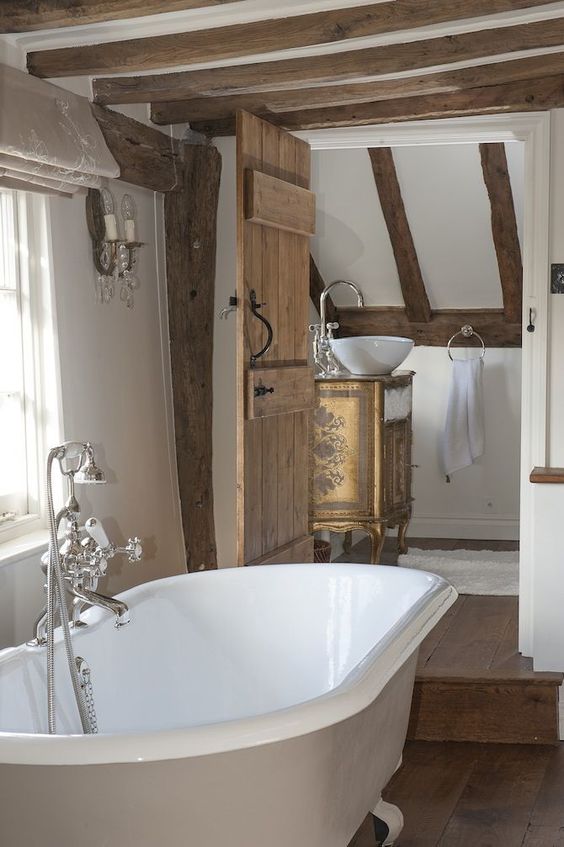 a Provence bathroom with stained wooden beams, a door and a refined vanity, a clawfoot barhtub and vintage fixtures