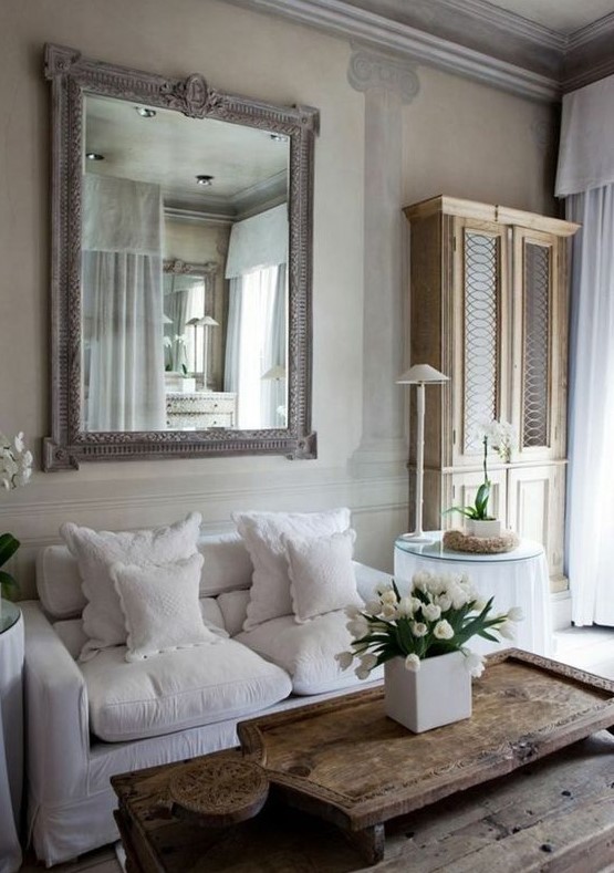 a Provence living room in neutrals, with a statement mirror, neutral furniture and a low wooden table plus mini round tables