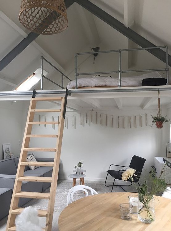 a Scandinavian home with a grey low sofa, a round table, a black chair and grey tables, a loft bedroom is super chic