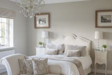 a chic neutral vintage bedroom with dove grey walls, creamy furniture, a crystal chandelier and printed textiles