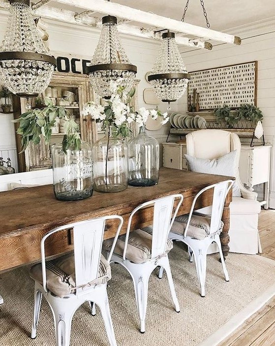 a chic vintage farmhouse dining area with crystal chandeliers, a sign, a shabby chic buffet, a wooden table and metal chairs