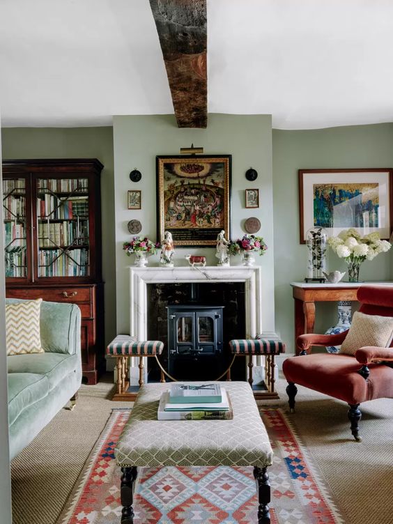 غرف معيشة كلاسيكية A-cozy-and-welcoming-vintage-living-room-with-light-green-walls-a-hearth-a-green-sofa-a-red-chair-printed-ottomans-a-gallery-wall