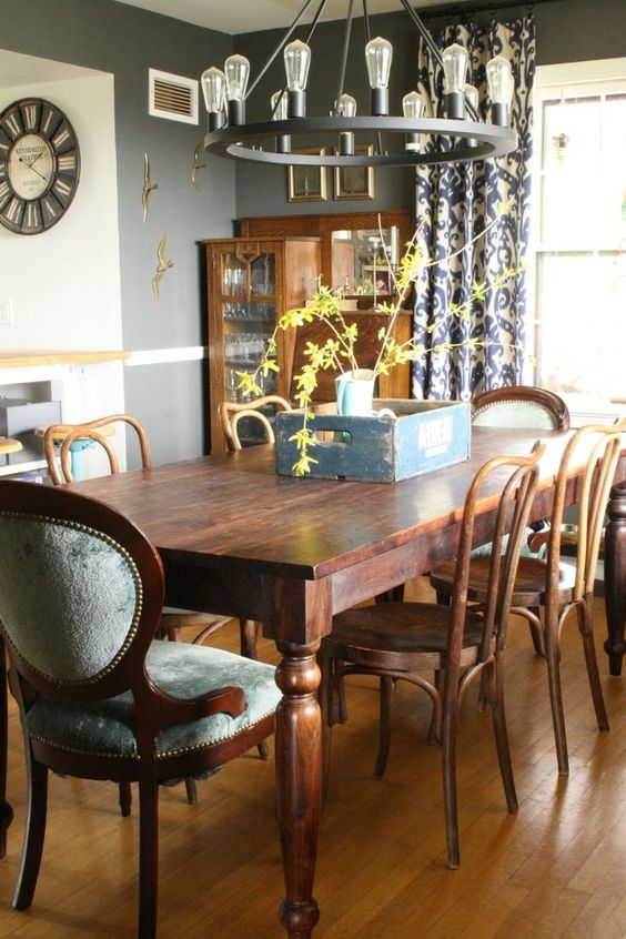 a cozy vintage dining room with a stained buffet, a dining table and grey upholstered and just stained chairs plus a round chandelier