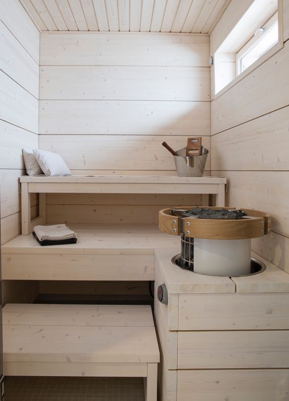 a cozy whitewashed wooden sauna with a skylight, three levels of benches and some aromatic pillows