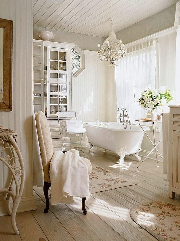 a creamy Provencal bathroom clad with wooden planks, with a glass storage unit, a clawfoot bathtub, printed rugs and shabby chic chairs and stools