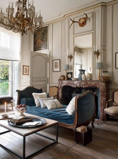 غرف معيشة كلاسيكية A-jaw-dropping-living-room-with-neutral-walls-and-paneling-a-fireplace-clad-with-marble-a-blue-daybed-a-chic-chandelier-and-artworks