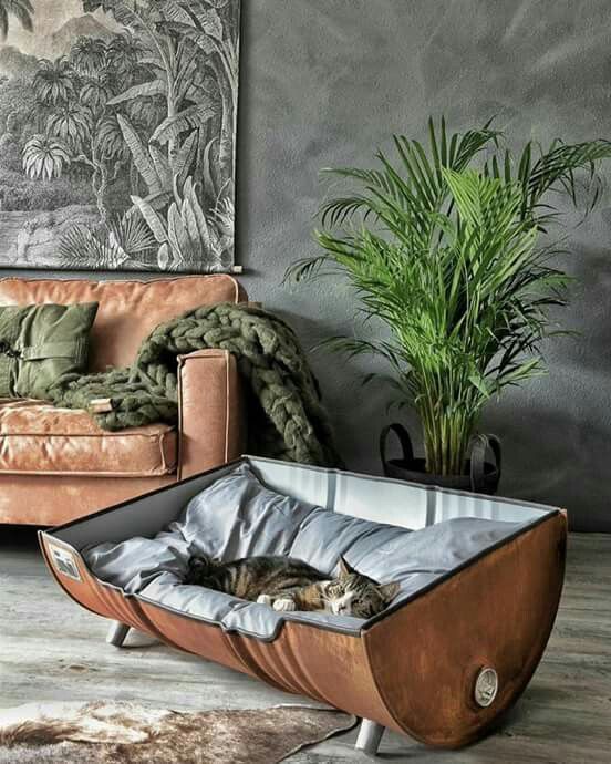 a large cat bed made of an old barrel with a pillow inside is a very cool and chic idea
