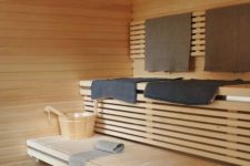 a large welcoming wood clad sauna with two floating benches and some towels is warming up