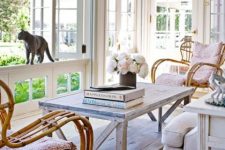 a light vintage sunroom with vintage wooden and rattan furniture, pastel and neutral textiles and blooms