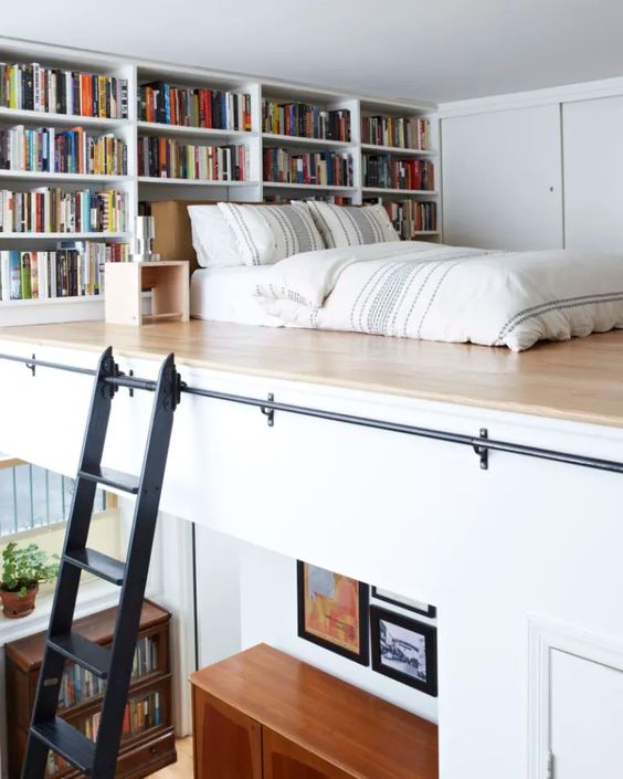 a loft bedroom with multiple bookshelves, a low bed on the floor and nightstands plus some storage units with sliding doors