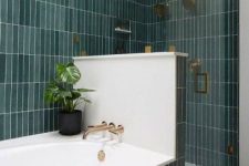 a lovely bathroom clad with green skinny tiles, with a half wall to divide the bathtub and shower space is amazing