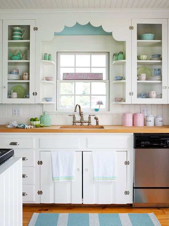 a lovely vintage kitchen with white cabinets, a white beadboard kitchen island,pink, blue and green accessories and neutral linens