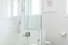 a minimalist bathroom with a black floor, a half wall that separates the toielt from the rest of the space, a shower-bathtub space