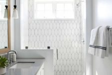 a modern coastal bathroom clad with navy and white tiles, a pony wall in the shower space and a white vanity