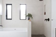 a neutral bathroom with mosaic tiles on the floor and neutral ones on the walls, a shower space with a pony wall that separates a shower and a bathtub