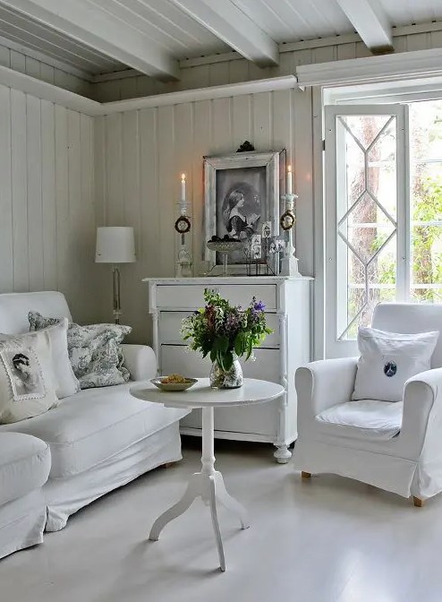 a neutral vintage living room with elegant and chic furniture, a white sideboard, candles and potted plants is very stylish