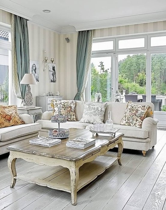 a refined vintage living room with chic neutral furniture, a low coffee table, striped walls and two color curtains plus floral pillows