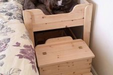 a simple wooden dog bed by the side of a human bed and with an additional staircase to make going up easy