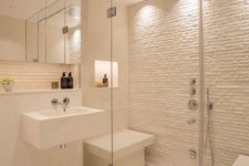 a small yet chic white steam room with a stone wall and mini benches plus built-in lights is cool