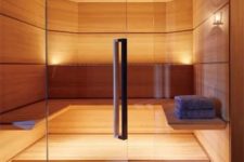 a small yet welcoming wood clad steam room with a couple of benches along the wall and built-in lights