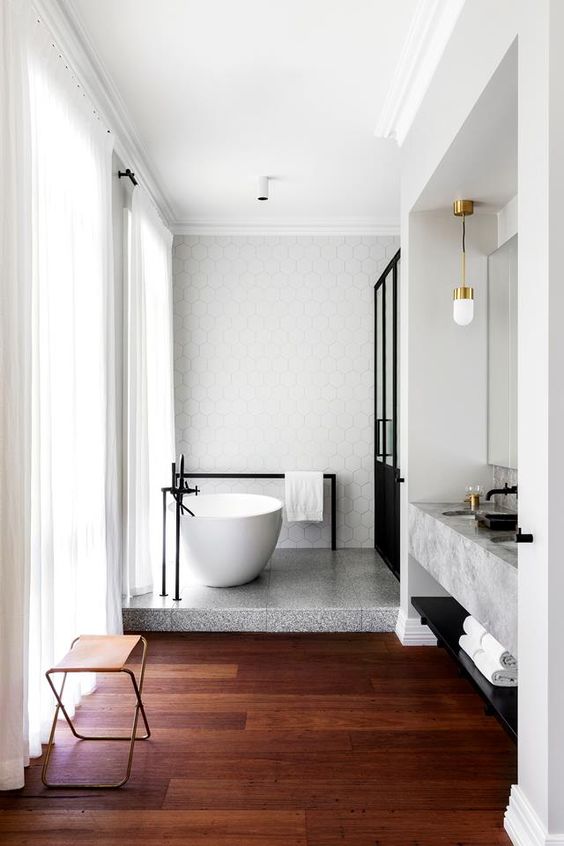 a stone platform under the bathtub is a cool idea to highlight this bathing oasis and give an edge to the bathroom