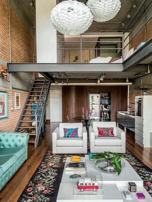 a stylish mid-century modern home with a brick accent wall, white furniture and a turquoise sofa, a bright rug and pillow, a sleeping and shower zone upstairs