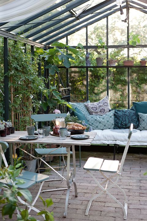 a vintage Nordic sunroom with some folding furniture and a large daybed, blue printed textiles and potted greenery