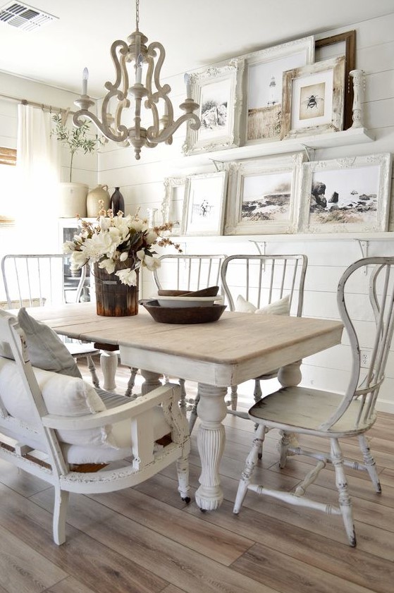 a vintage dining room with white shiplap walls, mismatched furniture, a large gallery wall and a vintage chandelier