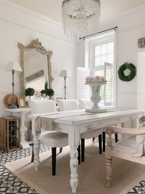 a vintage dining space with neutral and pastel furniture, blooms and greenery, a statement crystal chandelier and a refined mirror