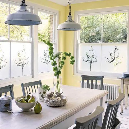 a vintage dining space with yellow walls, a white table, some grey chairs and pendant lamps, a wooden console table